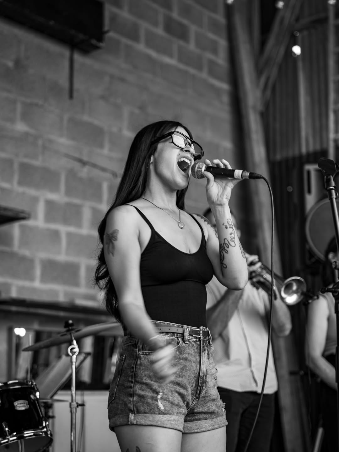 Alejandra en plein concert, micro en main, accompagnée d'un trompettiste